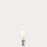 Dulora 4W B15 LED candle bulb in clear glass, glowing with 2200K extra warm white light.