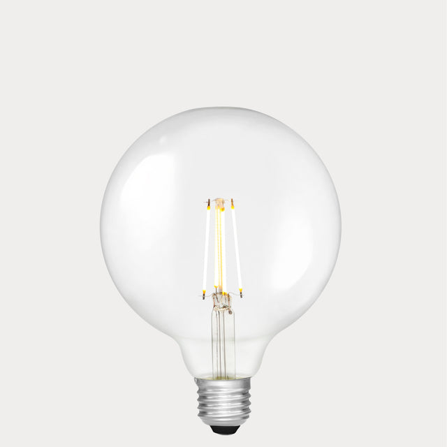 Dulora 7W E27 LED globe bulb in clear glass, glowing with 2700K warm white light.