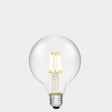 Dulora 8W E27 LED globe bulb in clear glass with AC/DC compatibility, glowing with 2700K warm white light.